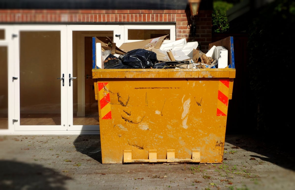 Roll-off dumpster container parked in a residential driveway for a home cleanout