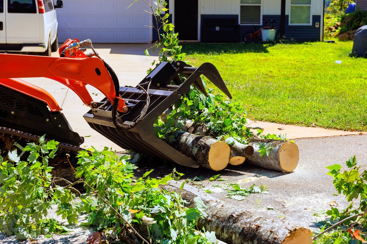 Skid steer clearing debris from a residential driveway