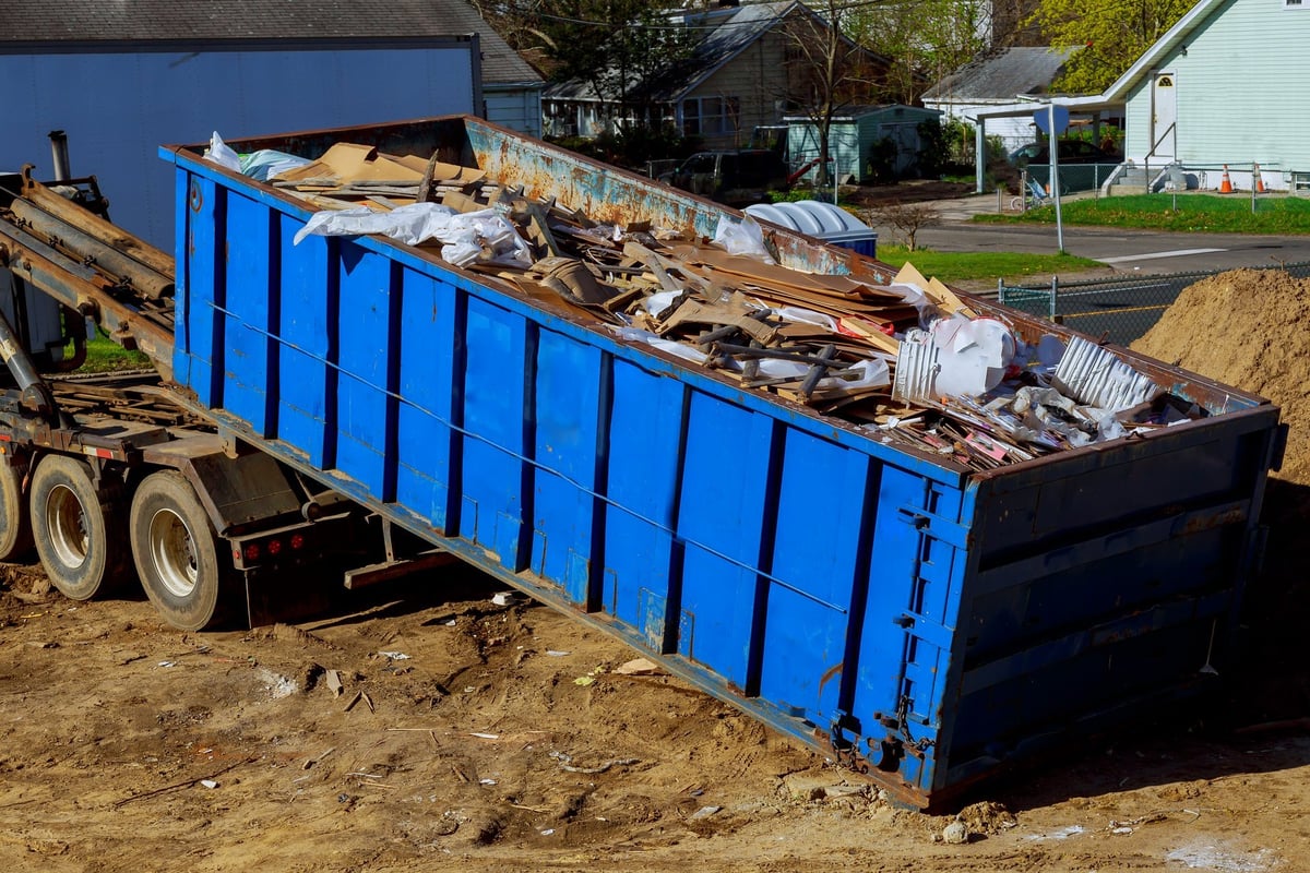Truck loading a full waste container during a junk removal pickup